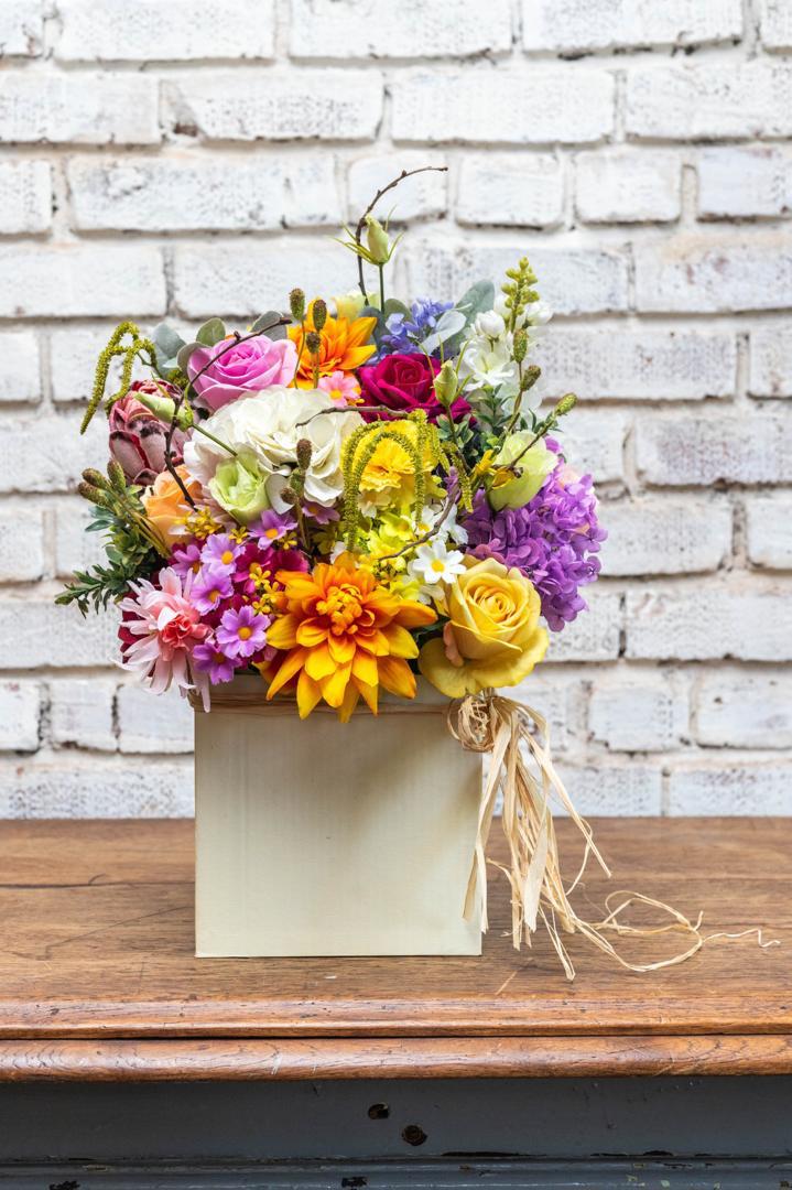 Bright artificial garden arrangement in a white box