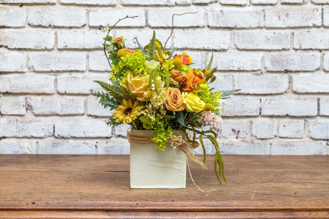 Yellow and orange artificial garden arrangement in a white box