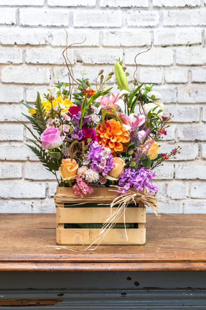 Bright mixed artificial flower crate arrangement